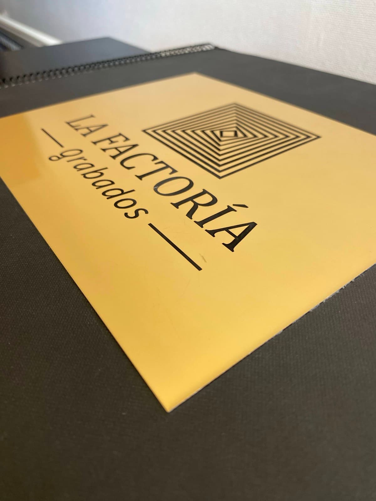 Logo de La Factoría Grabados grabado en placa dorada